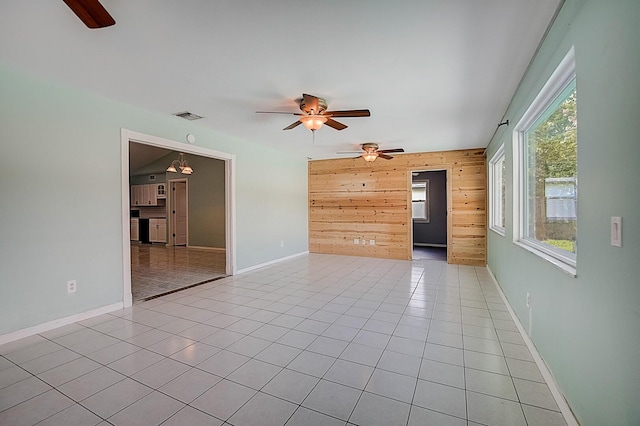 tiled spare room featuring wooden walls and ceiling fan
