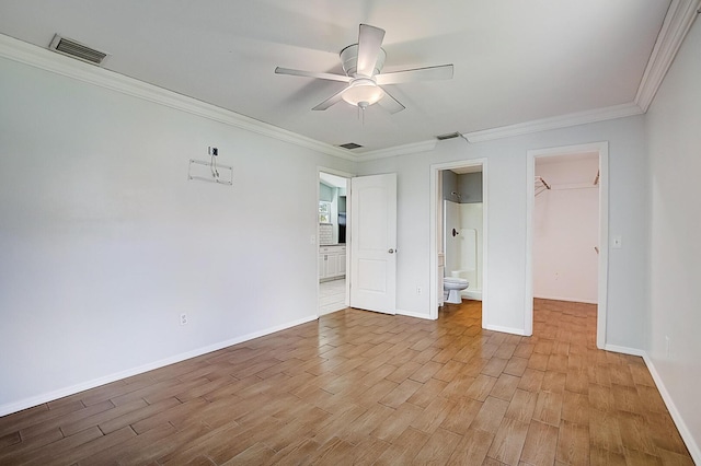 unfurnished bedroom featuring a closet, a walk in closet, ceiling fan, light wood-type flooring, and ensuite bath
