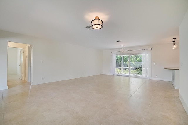 tiled spare room featuring a notable chandelier