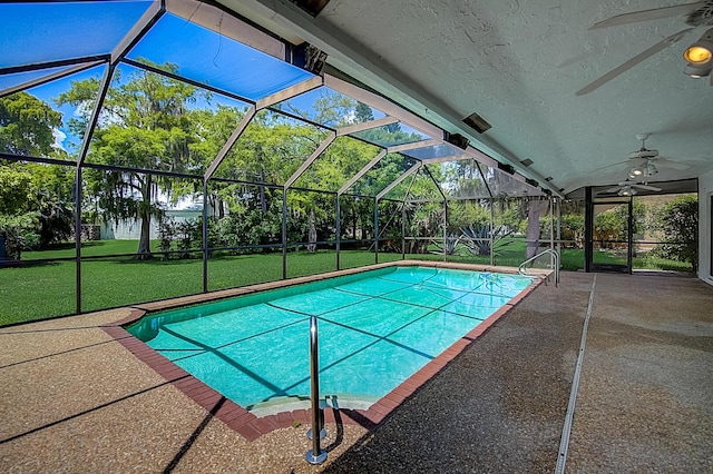 view of swimming pool featuring a yard, glass enclosure, ceiling fan, and a patio