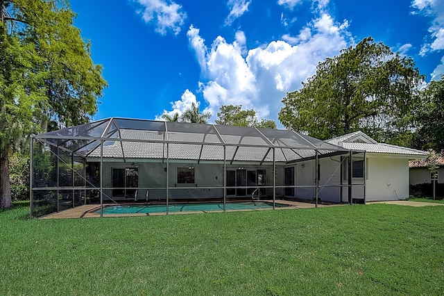 back of house with a lawn and glass enclosure