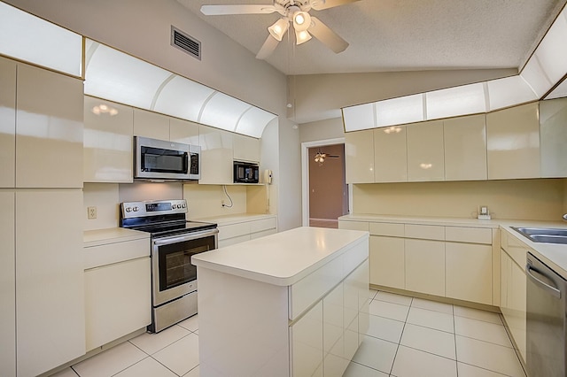 kitchen featuring a kitchen island, ceiling fan, appliances with stainless steel finishes, and lofted ceiling