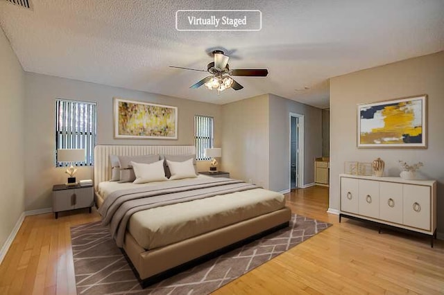 bedroom with a textured ceiling, ceiling fan, and hardwood / wood-style flooring