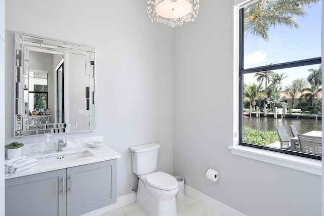 bathroom featuring tile flooring, toilet, a water view, and vanity with extensive cabinet space