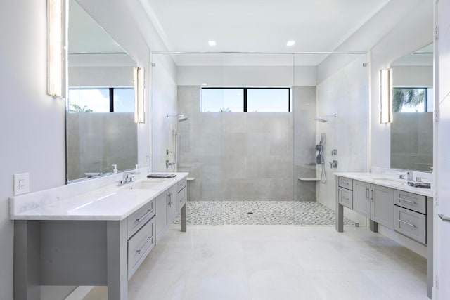 bathroom with tiled shower, tile flooring, plenty of natural light, and vanity