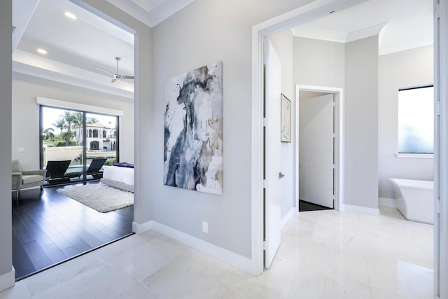 hallway with a tray ceiling and light tile flooring