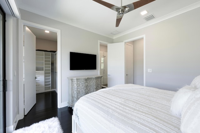 bedroom featuring ornamental molding, dark hardwood / wood-style floors, a spacious closet, a closet, and ceiling fan