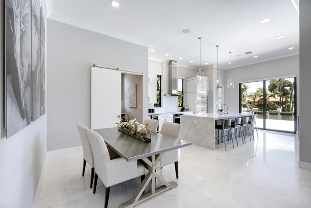 dining room with sink, a barn door, light tile flooring, and crown molding