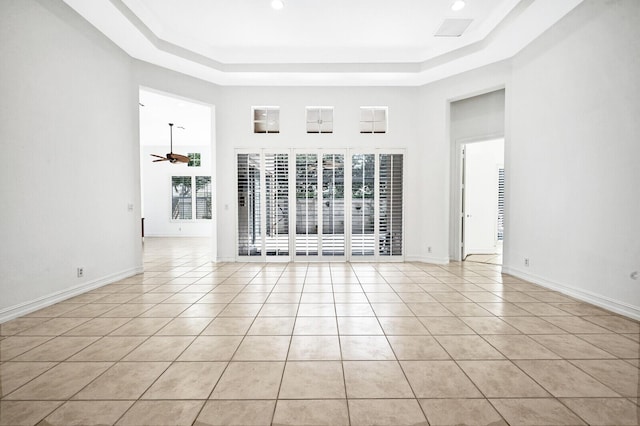 unfurnished room featuring light tile floors, a tray ceiling, and ceiling fan