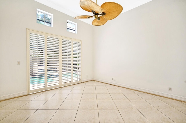 unfurnished room featuring light tile flooring, ceiling fan, and a towering ceiling