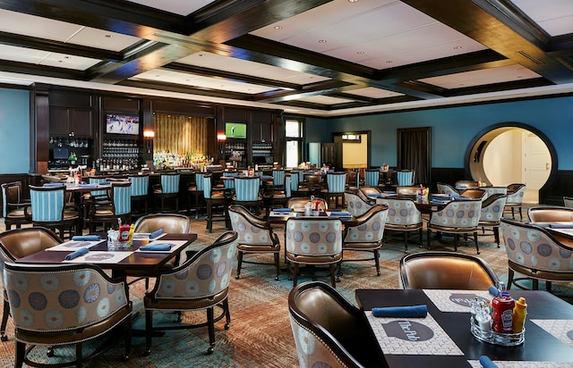 carpeted dining room featuring coffered ceiling, ornamental molding, bar area, and beamed ceiling