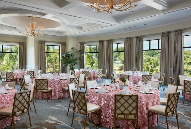 carpeted dining space featuring coffered ceiling, a healthy amount of sunlight, ornamental molding, and an inviting chandelier