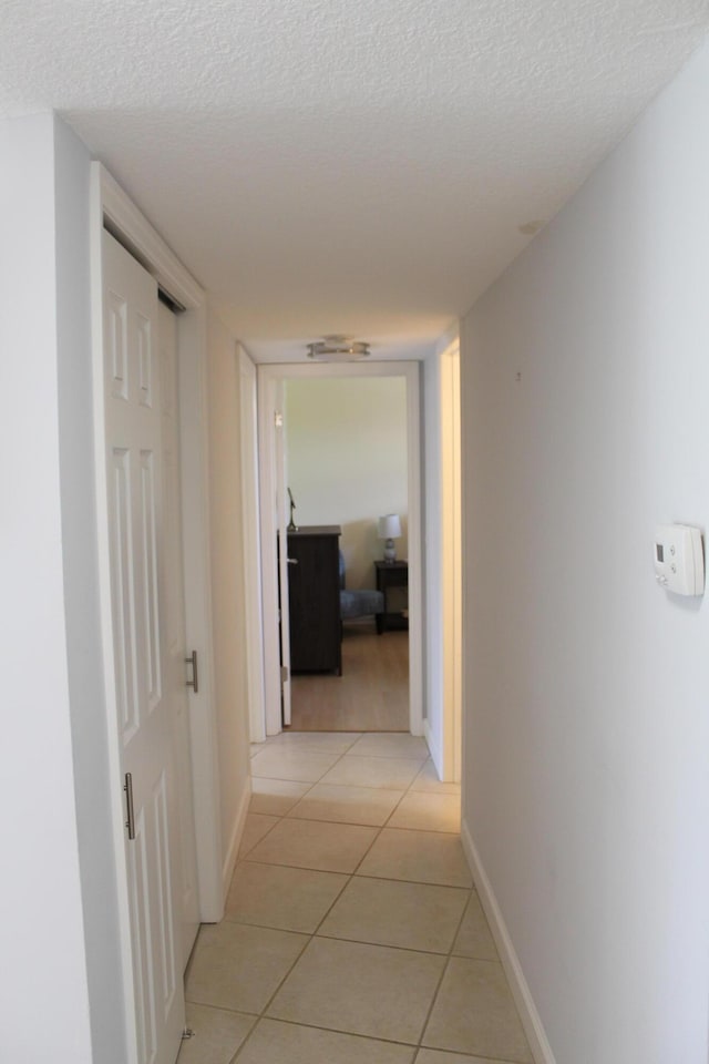 corridor featuring light tile floors and a textured ceiling