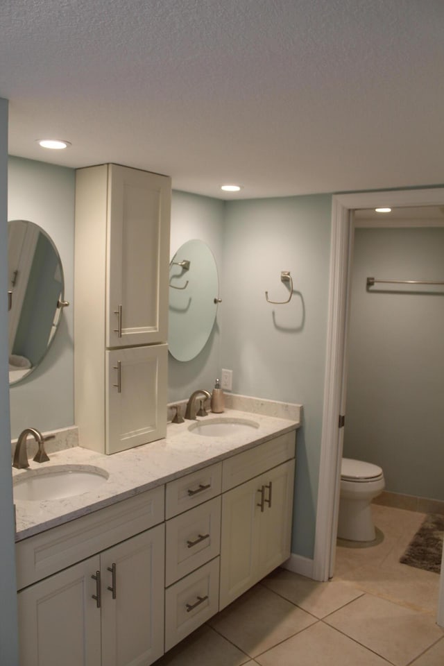 bathroom featuring double sink vanity, tile flooring, a textured ceiling, and toilet