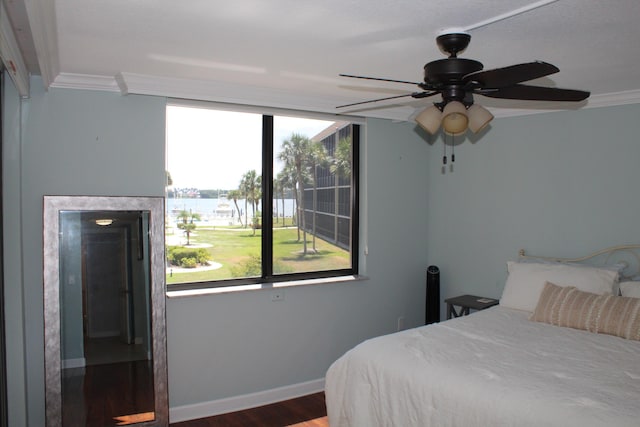 bedroom with ornamental molding, dark hardwood / wood-style flooring, ceiling fan, and a water view