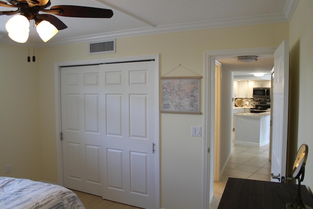 tiled bedroom with a closet, ceiling fan, and crown molding