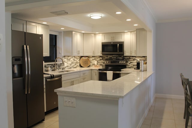 kitchen with kitchen peninsula, sink, appliances with stainless steel finishes, backsplash, and light stone countertops