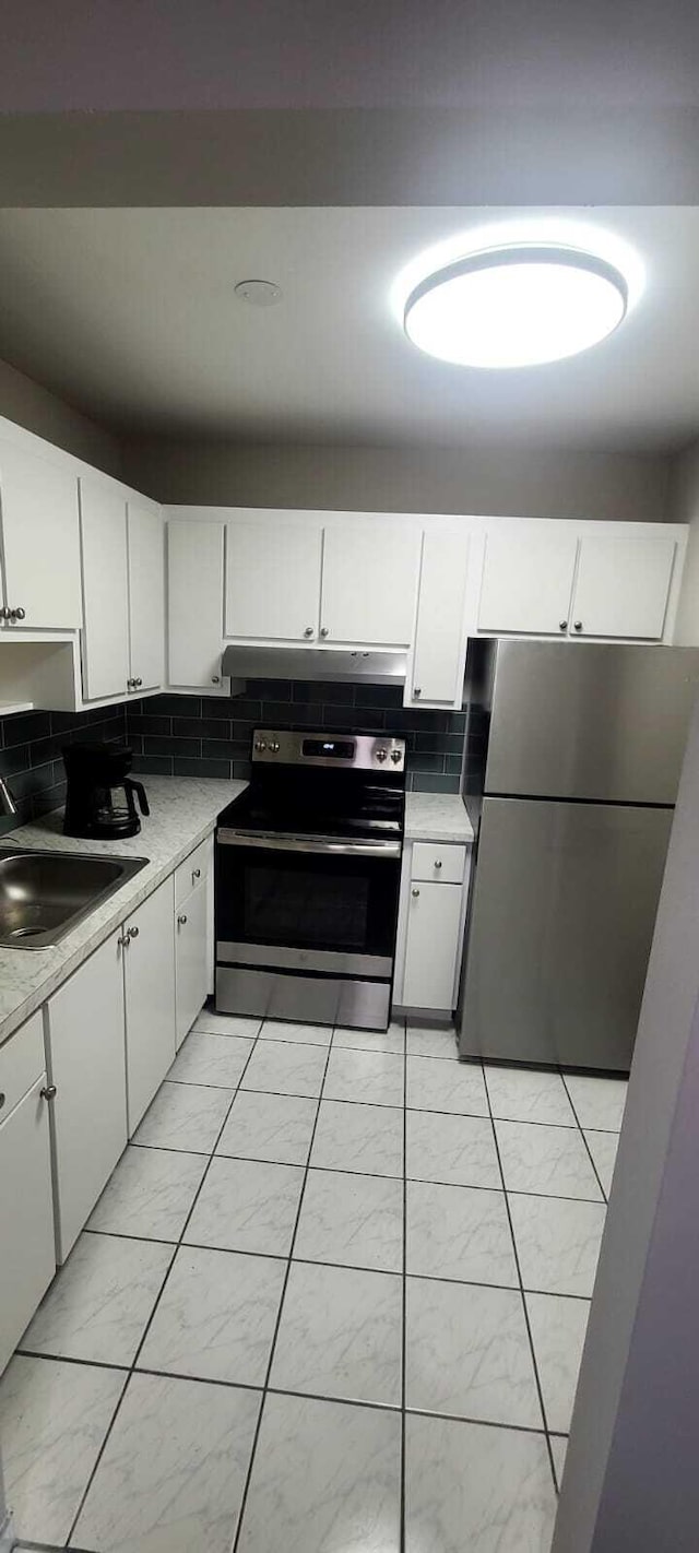 kitchen with backsplash, stainless steel appliances, white cabinetry, and sink