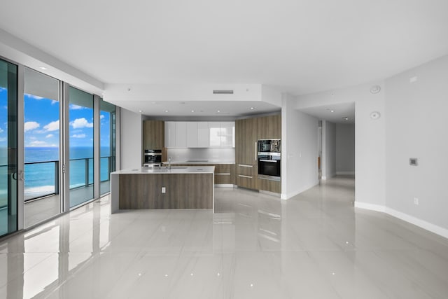 3100 N Ocean Dr Unit H-1509, Singer Island, FL 33404 - kitchen featuring modern cabinets, oven, a wall of windows, baseboards, and plenty of natural light