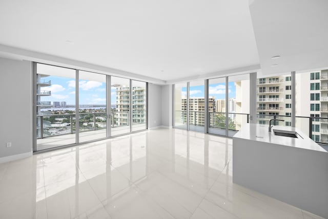 3100 N Ocean Dr Unit H-1509, Singer Island, FL 33404 - spare room featuring a view of city, a sink, light tile patterned flooring, a wall of windows, and baseboards