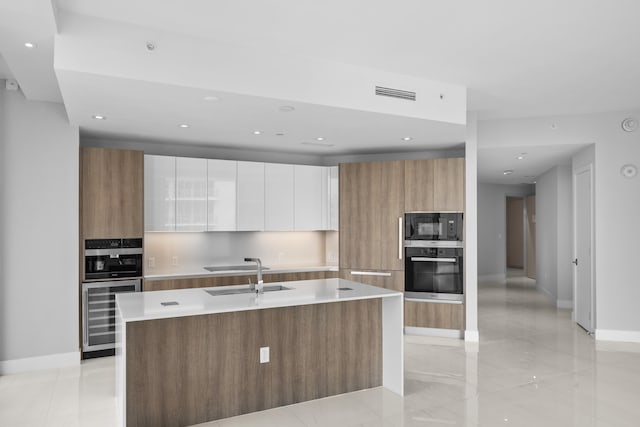 kitchen featuring wine cooler, white cabinetry, a kitchen island with sink, and appliances with stainless steel finishes