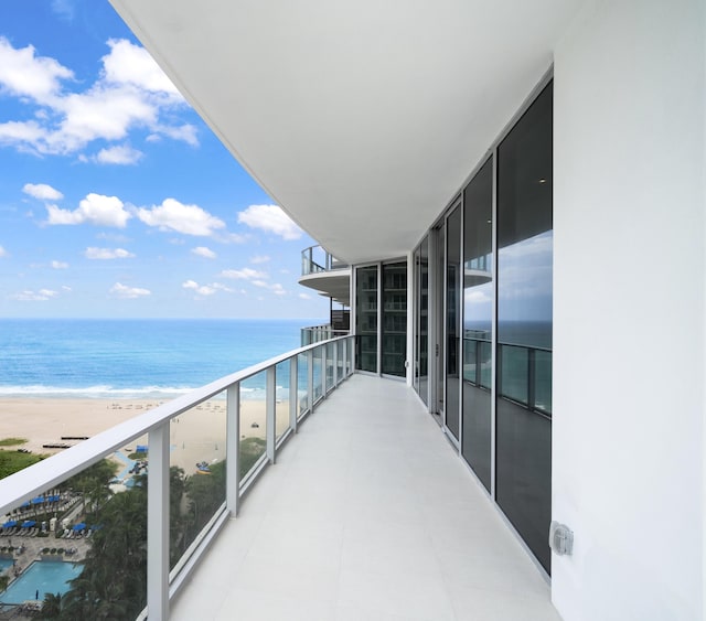 balcony featuring a view of the beach and a water view