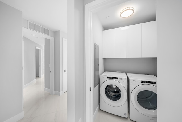 laundry room with washer and clothes dryer, light tile patterned flooring, and cabinets