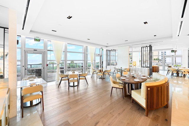 dining space featuring a tray ceiling, light hardwood / wood-style floors, and a wall of windows