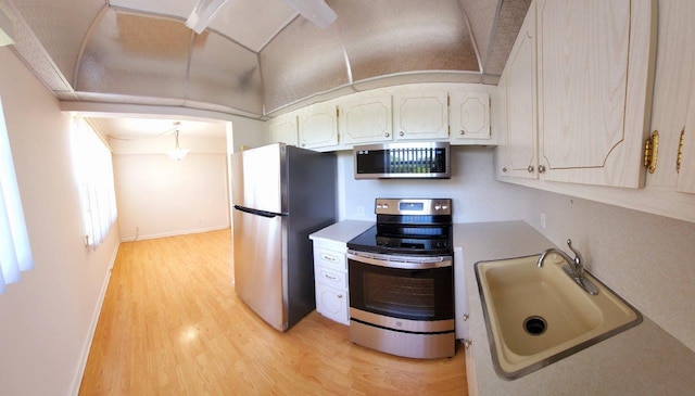 kitchen with white cabinets, stainless steel appliances, light wood-type flooring, and sink