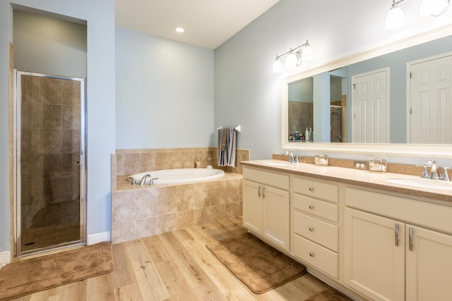 bathroom with independent shower and bath, oversized vanity, dual sinks, and hardwood / wood-style flooring