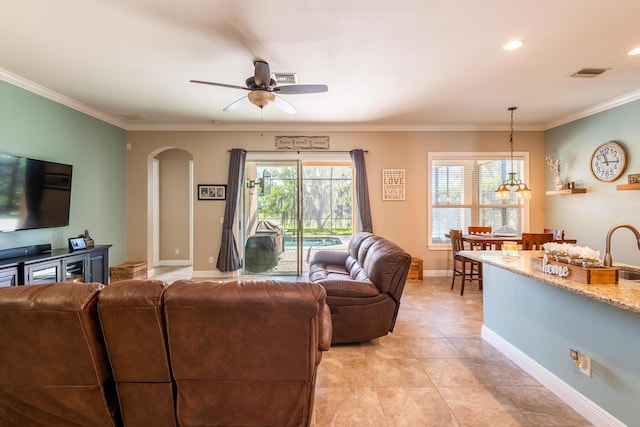 tiled living room with crown molding, sink, and ceiling fan with notable chandelier