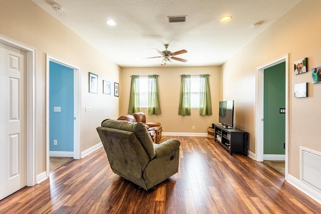 living room featuring dark hardwood / wood-style flooring, a textured ceiling, and ceiling fan