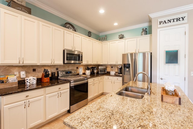 kitchen featuring ornamental molding, dark stone counters, sink, and stainless steel appliances