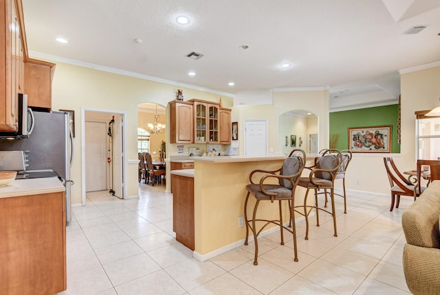 kitchen with light tile floors, a chandelier, tasteful backsplash, a breakfast bar area, and ornamental molding