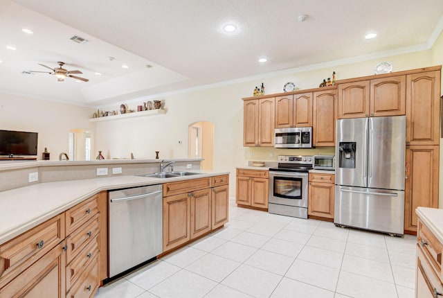 kitchen with stainless steel appliances, light tile floors, ceiling fan, a tray ceiling, and sink