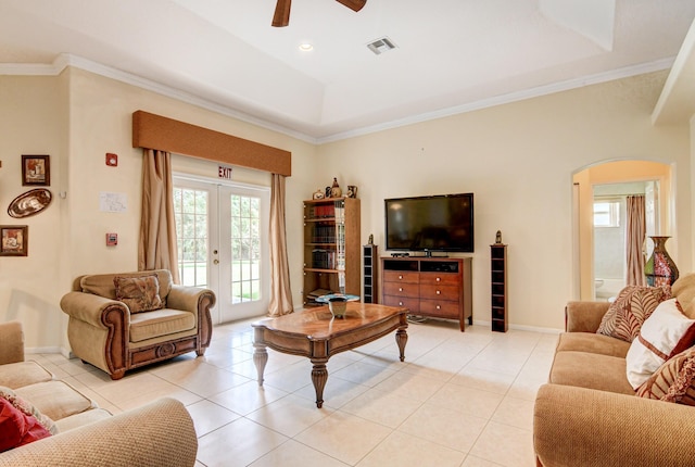 living room featuring ceiling fan, light tile floors, a raised ceiling, french doors, and ornamental molding