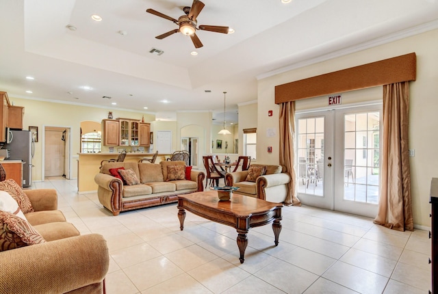 living room with a raised ceiling, ceiling fan, french doors, and crown molding