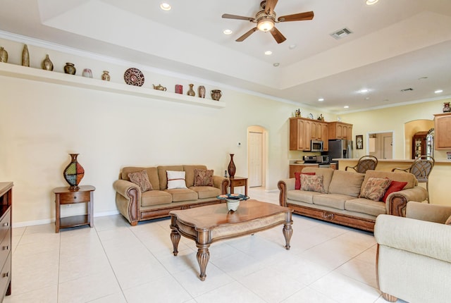 tiled living room with a tray ceiling, ornamental molding, and ceiling fan