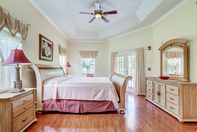 bedroom with ceiling fan, wood-type flooring, a raised ceiling, and ornamental molding