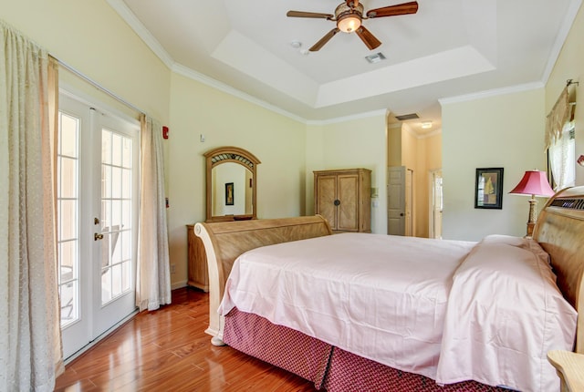 bedroom featuring french doors, ceiling fan, a raised ceiling, hardwood / wood-style floors, and ornamental molding