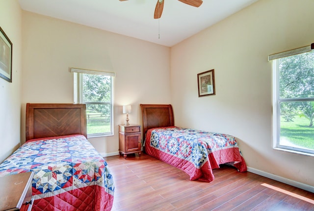 bedroom featuring ceiling fan, hardwood / wood-style flooring, and multiple windows