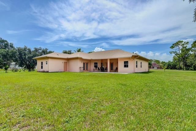 rear view of house featuring a lawn and a patio