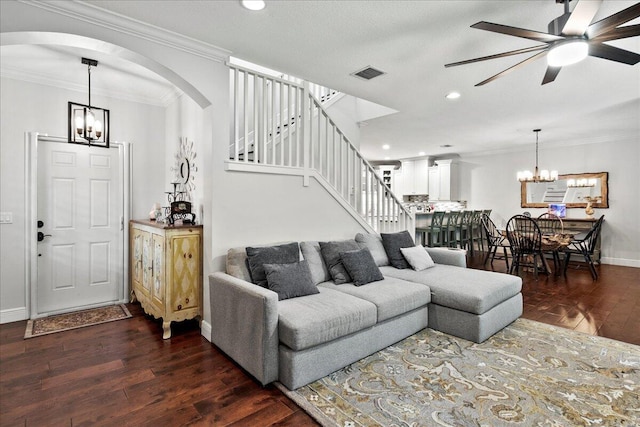 living room with crown molding, ceiling fan with notable chandelier, and dark wood-type flooring