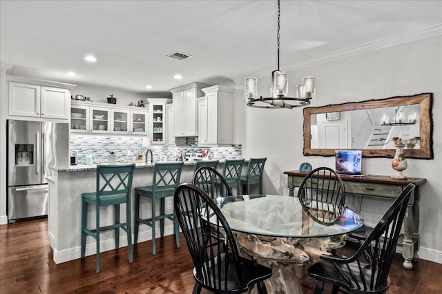 dining space featuring a chandelier, dark hardwood / wood-style floors, and crown molding