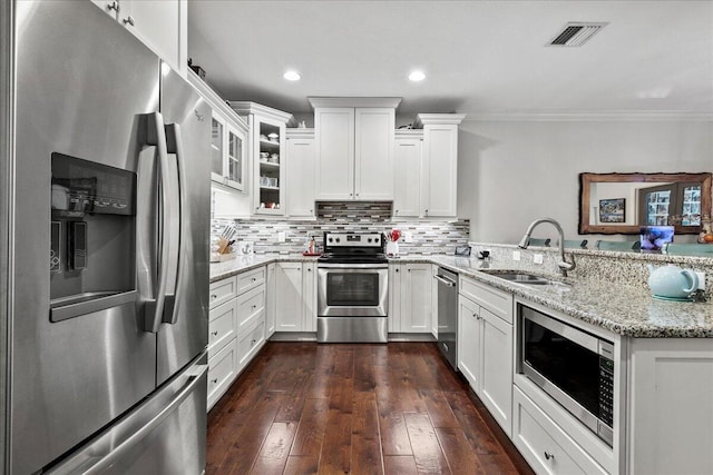 kitchen with dark wood-type flooring, stainless steel appliances, light stone counters, tasteful backsplash, and ornamental molding