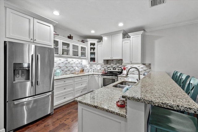 kitchen with sink, dark hardwood / wood-style flooring, appliances with stainless steel finishes, a breakfast bar area, and tasteful backsplash