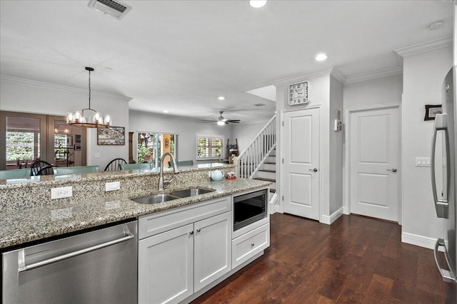 kitchen with white cabinetry, ceiling fan with notable chandelier, appliances with stainless steel finishes, sink, and light stone counters