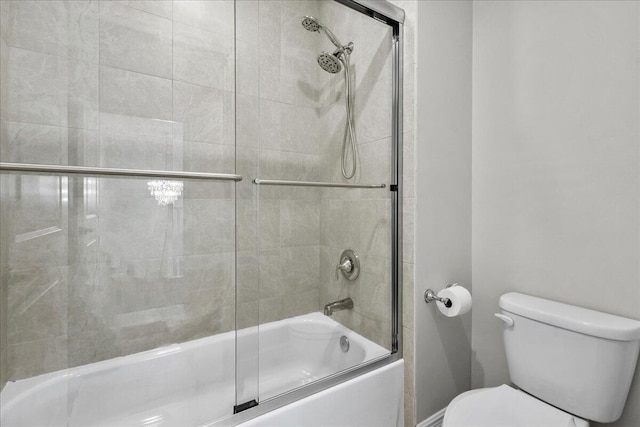 bathroom featuring toilet and bath / shower combo with glass door