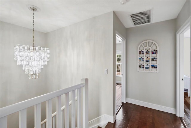 hallway featuring an inviting chandelier, plenty of natural light, and dark hardwood / wood-style flooring