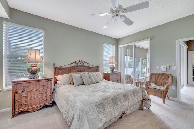 bedroom featuring a textured ceiling, ceiling fan, and light colored carpet